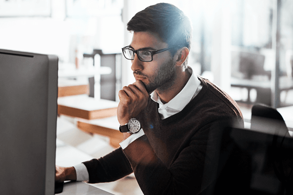 Serious businessman reads report on desktop computer