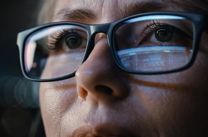 Close up of hand looking at monitor with reflection in glasses. tech trends 2023, strategic IT trends