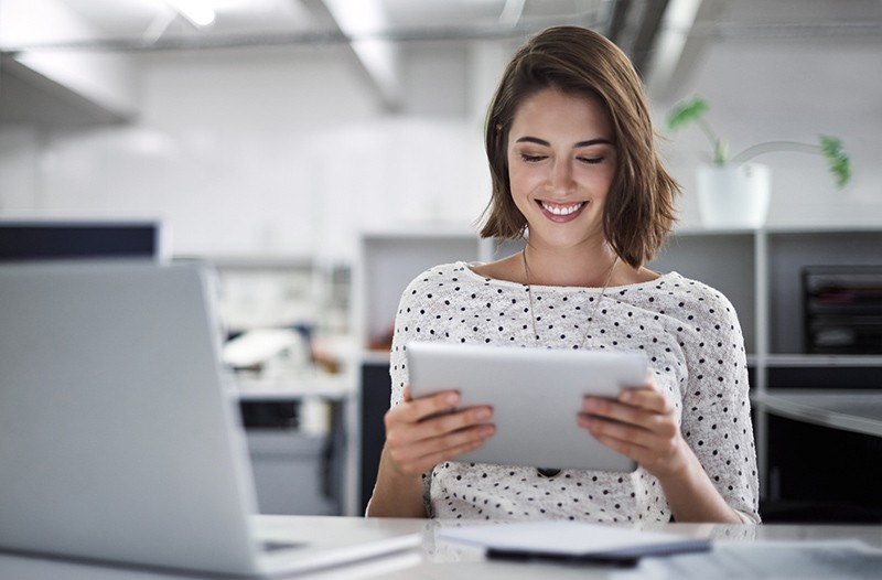 Smiling businesswoman on tablet device in bright office