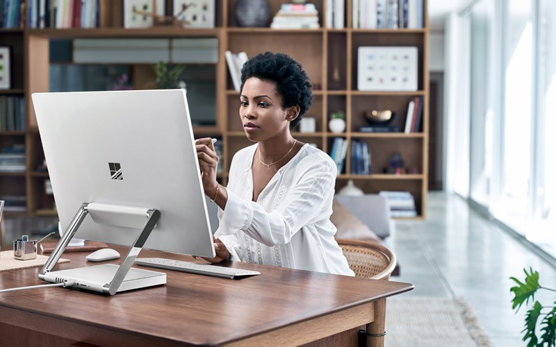 Woman working remotely in home office using Surface Studio