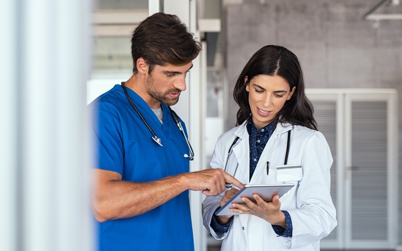 Two doctors collaborating over tablet device