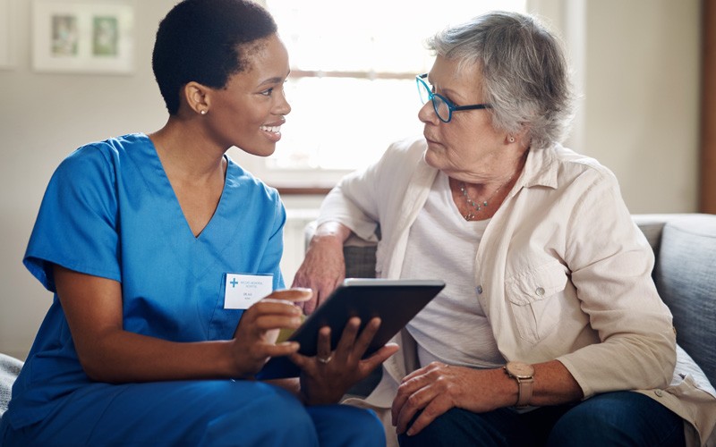 Nurse with tablet explains treatment options to elderly patient 