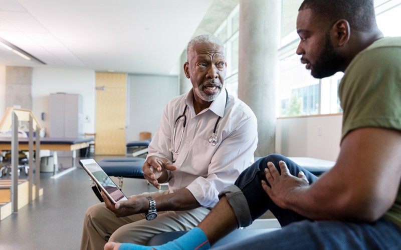 Physical therapist on tablet device shows results to patient